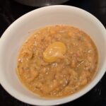 A bowl of beige pea soup topped with a dollop of brownish mustard