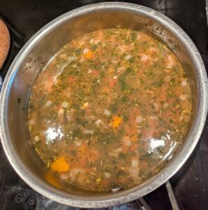 The soup pot with tomato sauce added, changing the broth color.