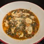 A finished bowl of soup, topped with a spoonful of finely grated hard cheese.