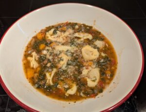 A finished bowl of soup, topped with a spoonful of finely grated hard cheese.