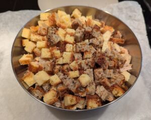 A stainless steel mixing bowl of 1.6L capacity, nearly full of freshly cut bread cubes.