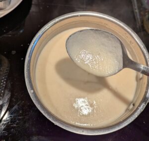 The finished pot of gravy, showing it pouring off a spoon to demonstrate the consistency you want.
