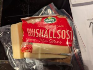 A large block of cheese, with a chunk sliced off one end.