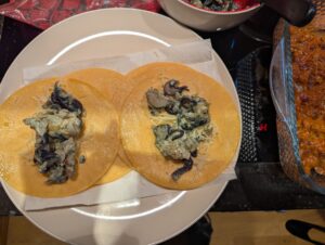 A couple of enchiladas mid-assembly, side by side on top of the double stack of fried tortillas.