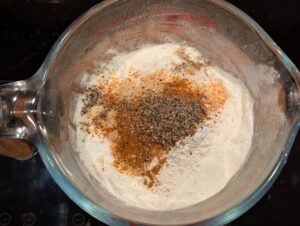 The flour cup with a pile of mixed seasonings visible on the surface