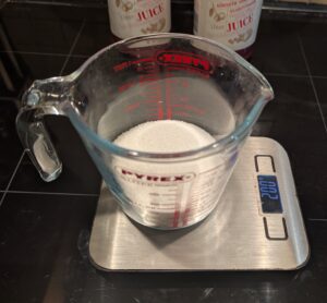 A Pyrex measuring cup with sugar sits on a digital scale