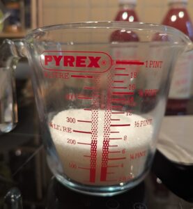 A Pyrex measuring cup of sugar showing the volume from the side