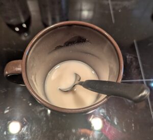Cloudy yeast water in the mug with a stirring spoon