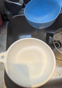 Sugar pouring through a funnel into the jug