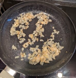 Chopped onion frying in a pan.