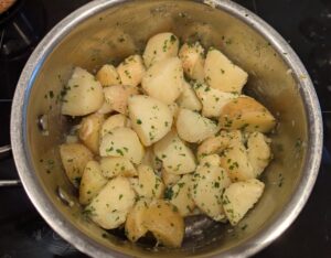 A pan of boiled potatoes with butter and parsley