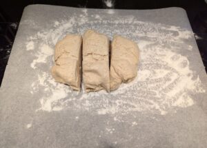 The dough ball on a floured piece of baking paper, cut into rough thirds.