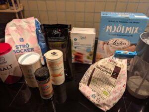 A collection of dry baking ingredients including flour, white and brown sugars, baking powder, and xanthan gum