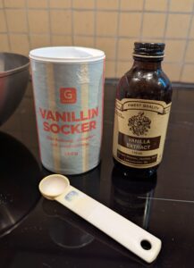 A container of vanillin sugar next to a bottle of vanilla extract