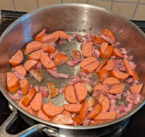 Sliced smoked sausage added into the pan