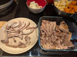 Bowl of pork mostly rib bones next to a dish of the meat off them