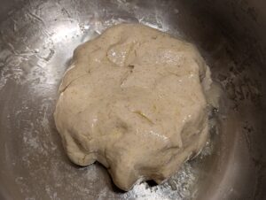 Oil-coated ball of now raised dough inside the oiled bowl