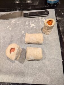 Wrapped sausage sections, with a couple turned up on the paper to show their ends