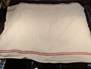 The towel covered rolls on the baking sheet
