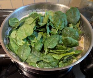 Pan of risotto with fresh baby leaf spinach just added in