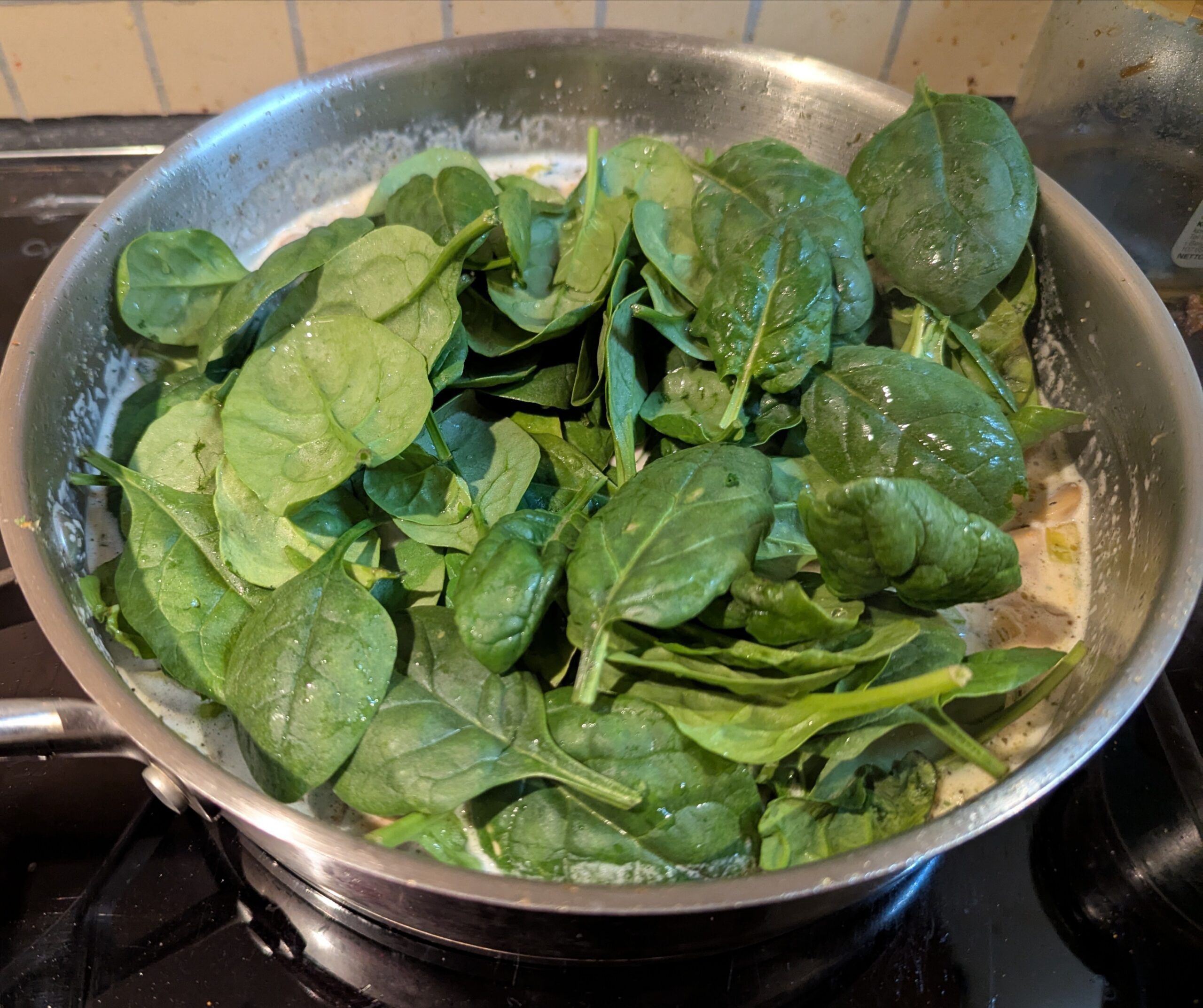 Pan of risotto with fresh baby leaf spinach just added in