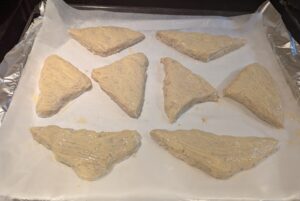 triangles of dough sitting on baking paper on a foil-covered baking sheet