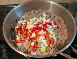 Pan of frying ground meat with chopped onion and red pepper just added