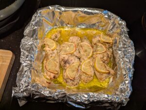 Baking dish of cooked chicken breast pieces topped with half slices of lemon