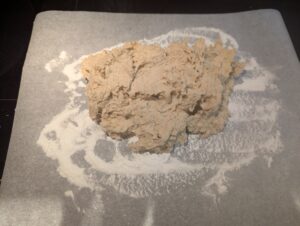 Very soft mound of dough on a floured sheet of baking paper