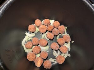 Sliced onions and meatballs in the pressure cooker's inner pot