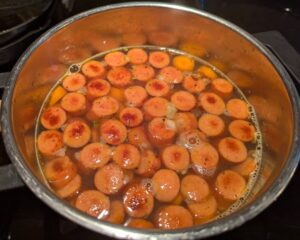 Soup just starting to cook together in the pot, with the sausage slices floating on top.