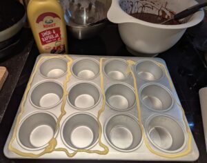 A cupcake tin with stripes of squeeze margarine on top between the compartments