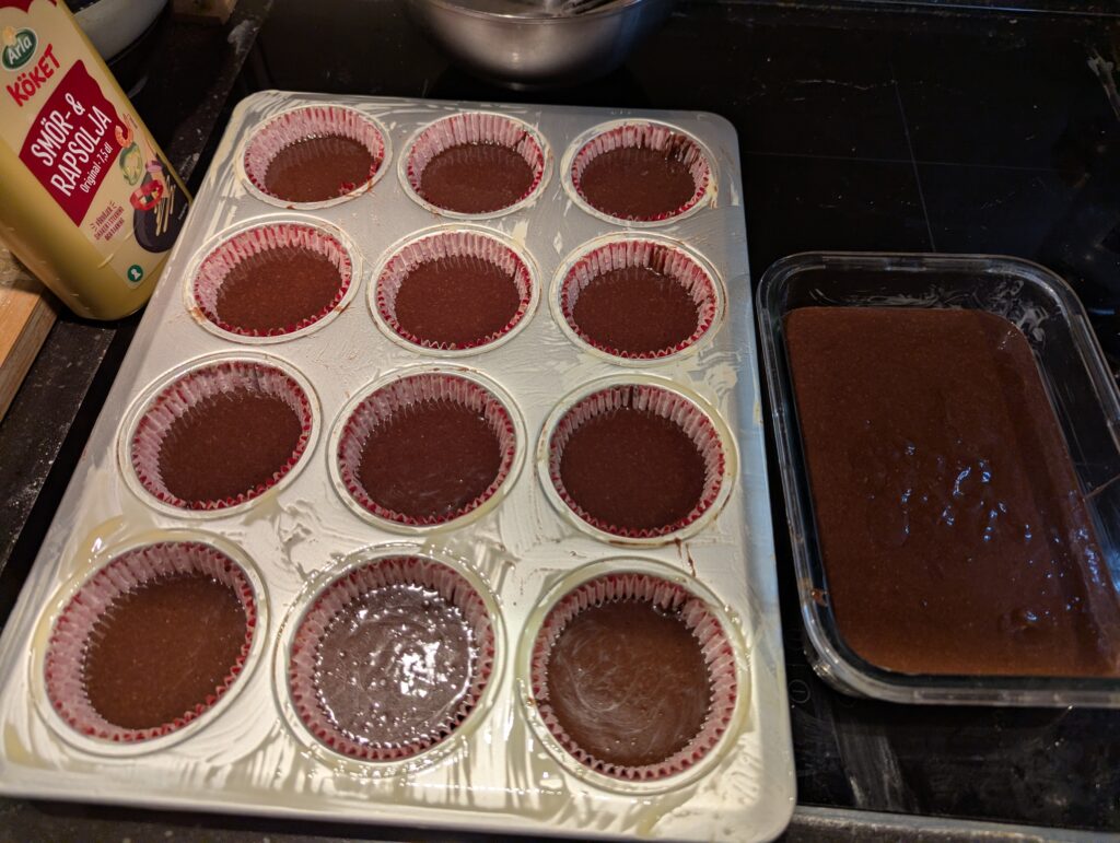 A cupcake pan of batter, next to a smallish glass pan with the rest