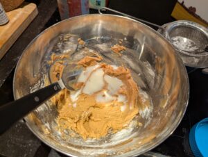 icing in progress, with a spoonful of milk about to be stirred in