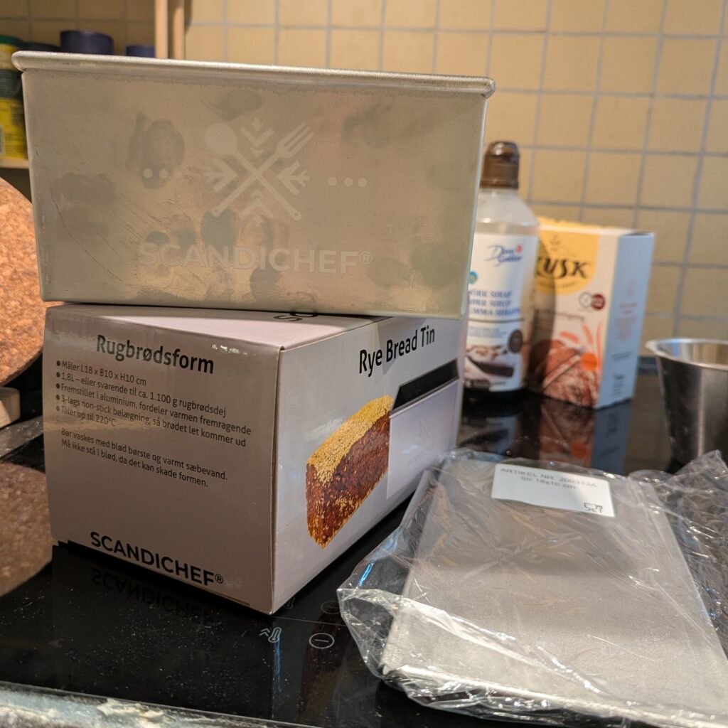 A bread pan sits on top of the box it came in, with its sliding lid over to the side