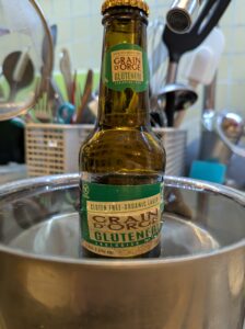 A bottle of beer sits in a pan of warm water