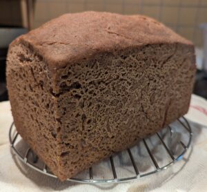 Finished loaf of bread cools on a rack.