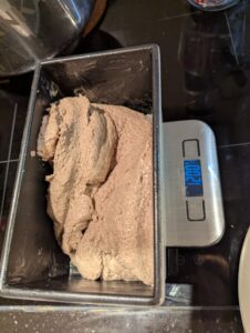 Bread transferred to the pan, on a digital scale showing the weight
