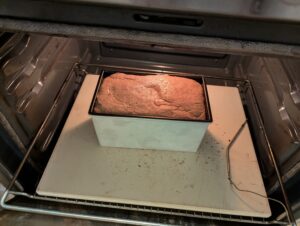 Pan of bread dough sits on a baking sone low down in the oven