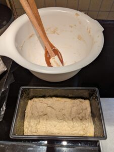 Batter in the pan with the scraped mixing bowl behind it