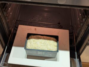 Bread pan going into the oven on a baking stone